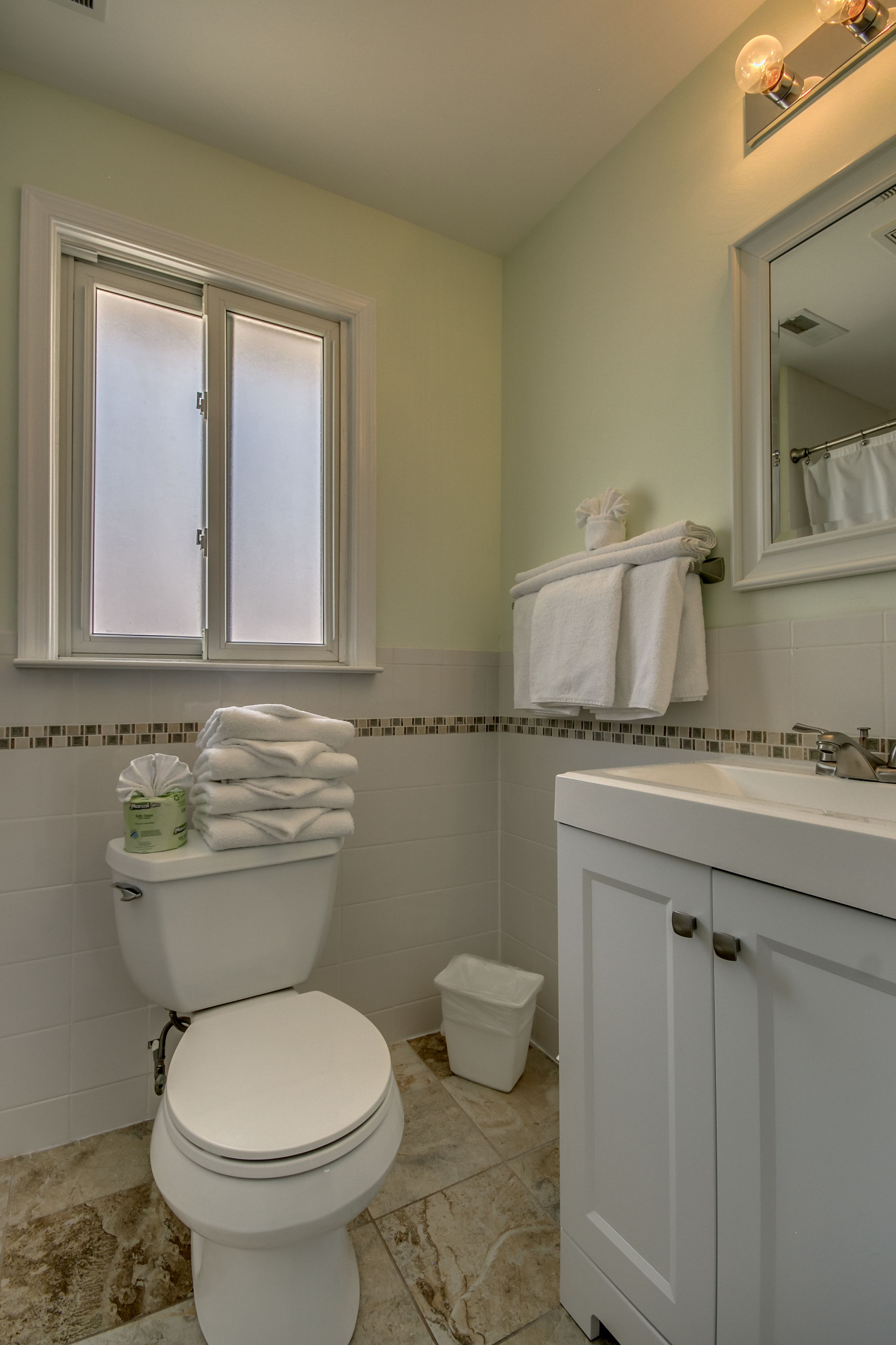 A bathroom with a toilet, sink, and mirror.