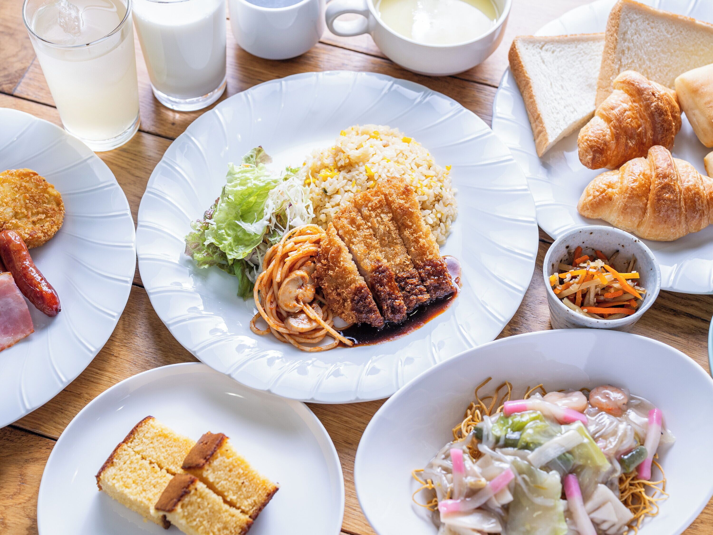 A table with various dishes including fried chicken, rice, noodles, and a salad.