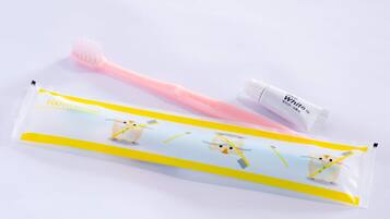 A tube of toothpaste and a toothbrush with a yellow and white packaging.