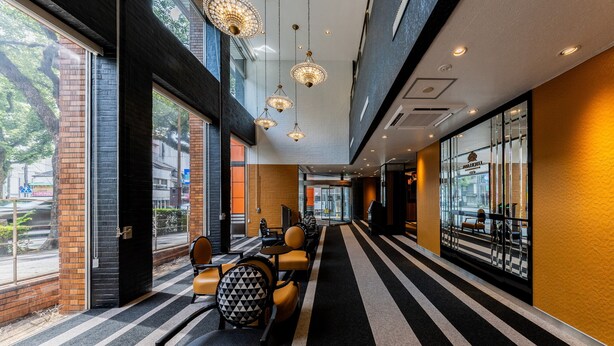 A hotel lobby with a striped carpet, modern furniture, and large windows offering views of the outside. - APA Hotel Nagasaki Dejima (Nagasaki)