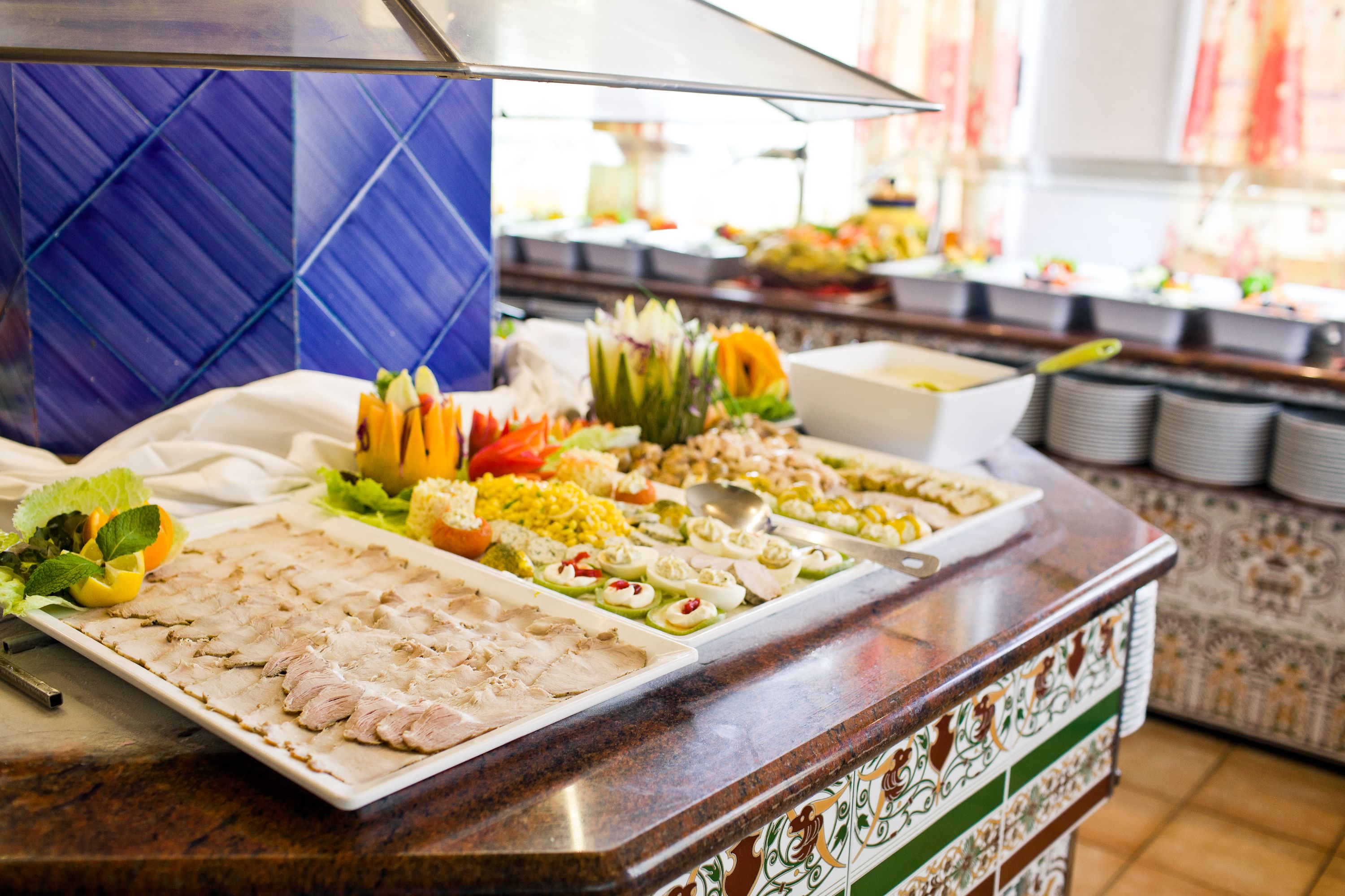 Ein Buffet mit verschiedenen Speisen, darunter Aufschnitt, Obst und Gemüse.