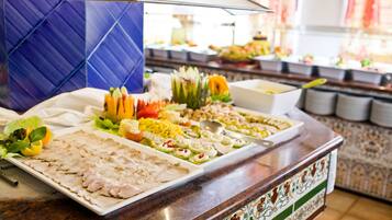 Ein Buffet mit verschiedenen Speisen, darunter Aufschnitt, Obst und Gemüse.