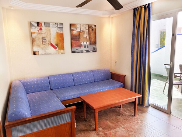 A room with a blue sofa, a wooden table, and two abstract paintings on the wall.