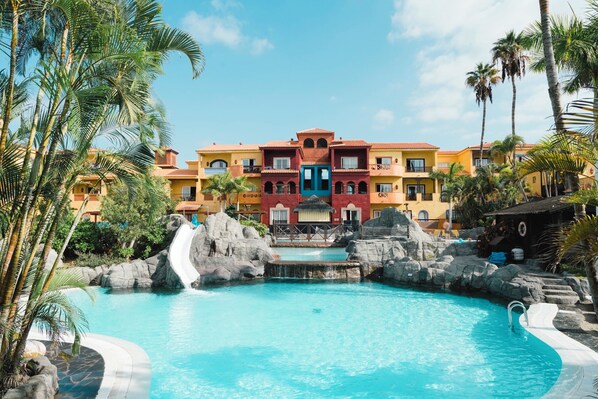 A resort with a pool, palm trees, and a building with multiple balconies. - Park Club Europe - All Inclusive (Arona)