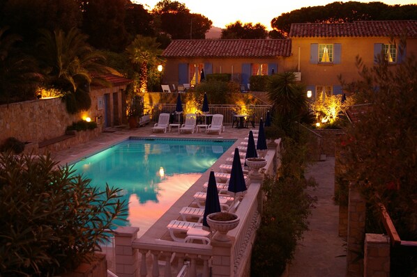 Una piscina al aire libre, sombrillas, sillones reclinables de piscina