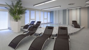A modern indoor pool area with lounge chairs and a central pool. - Clarion Congress Hotel Ostrava (Ostrava)