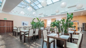 A spacious indoor dining area with wooden tables and chairs, large windows, and hanging paper lanterns. - Clarion Congress Hotel Ostrava (Ostrava)