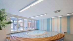 A spa area with a hot tub, wooden bench, and a large window offering a view of the outside. - Clarion Congress Hotel Ostrava (Ostrava)