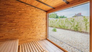 A wooden interior with a bench, a large window, and a view of a garden and building outside. - Clarion Congress Hotel Ostrava (Ostrava)