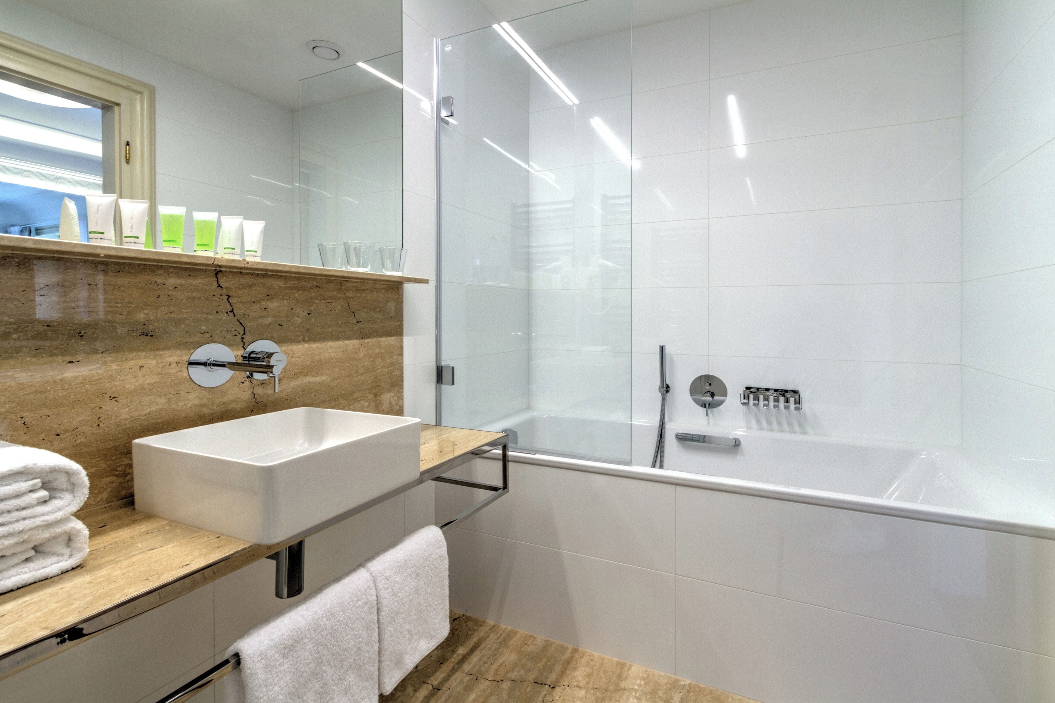 A modern bathroom with a white sink, a glass shower enclosure, and a wooden vanity.