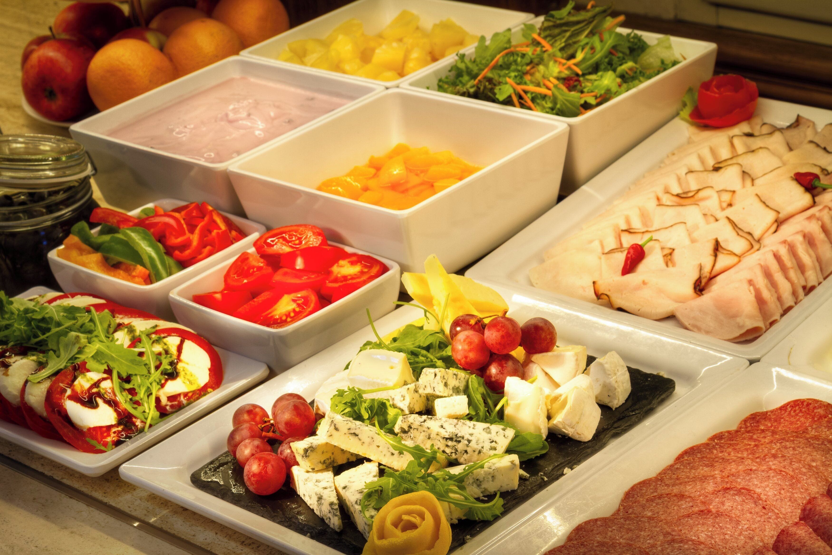 A buffet with various food items including fruits, cheeses, and meats.