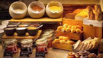 A buffet with various food items including bread, pastries, and jams.