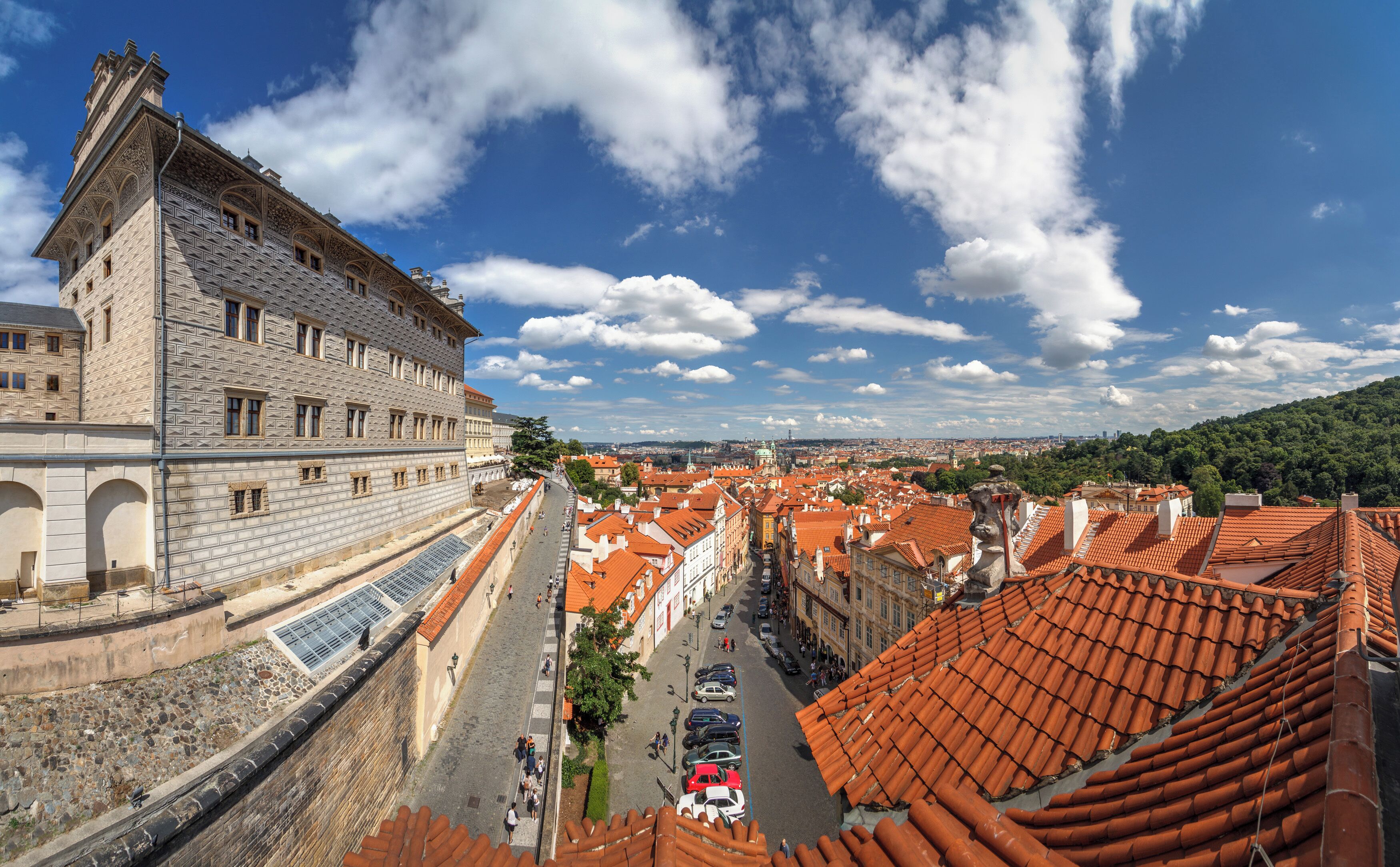 A historic building with intricate stonework, a cobblestone street, and traditional red-tiled roofs.
