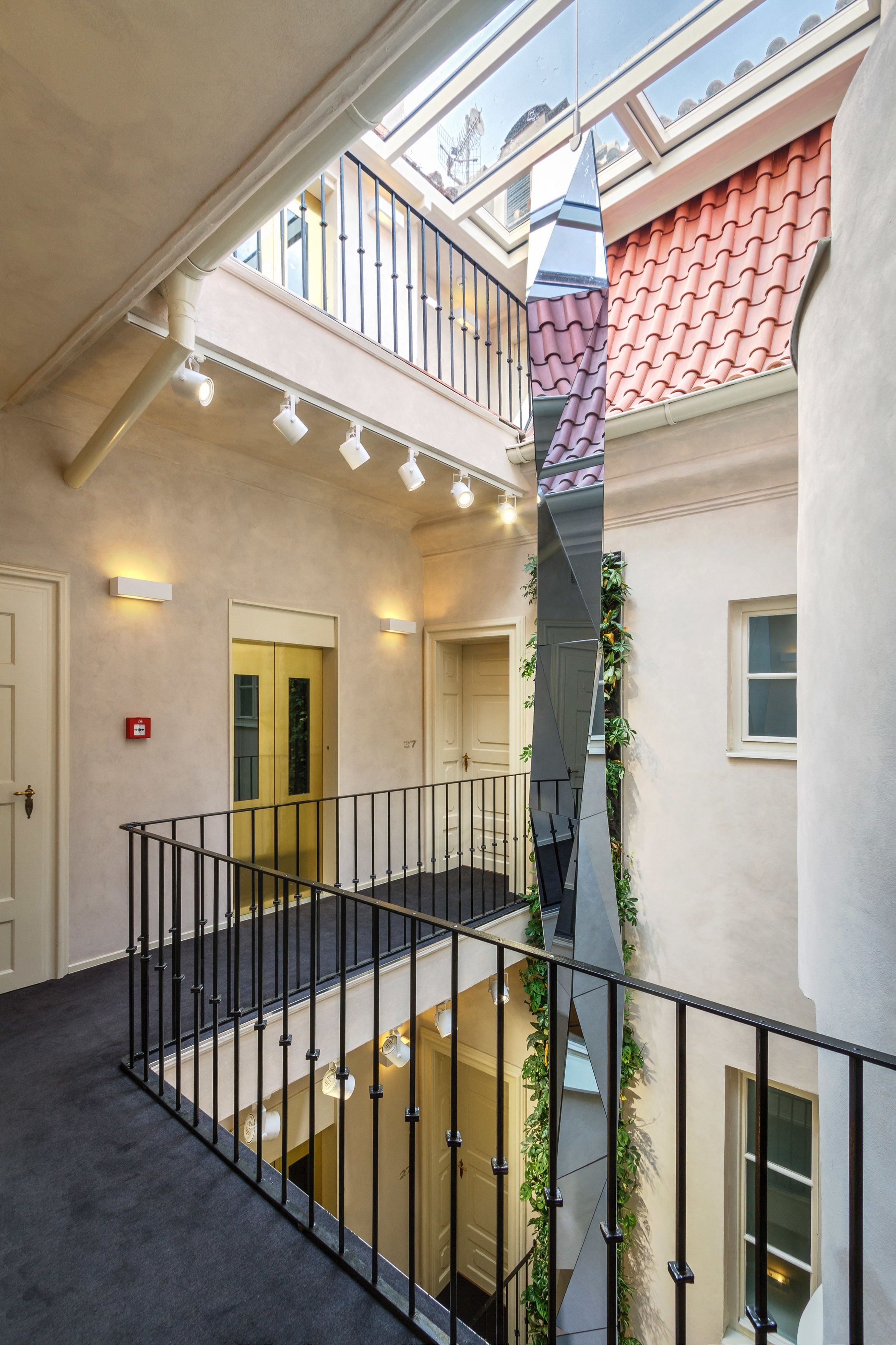 Un intérieur à plusieurs niveaux, doté d’un escalier central, de nombreuses portes et d’une verrière.