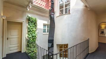 A multi-level interior with a staircase, a white door, and a green plant wall.