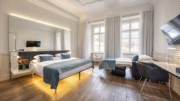Et moderne hotelværelse med en stor seng, et skrivebord, en stol og et fjernsyn.