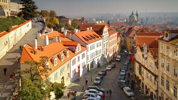 A historic street with traditional architecture, cobblestone pavement, and parked cars.