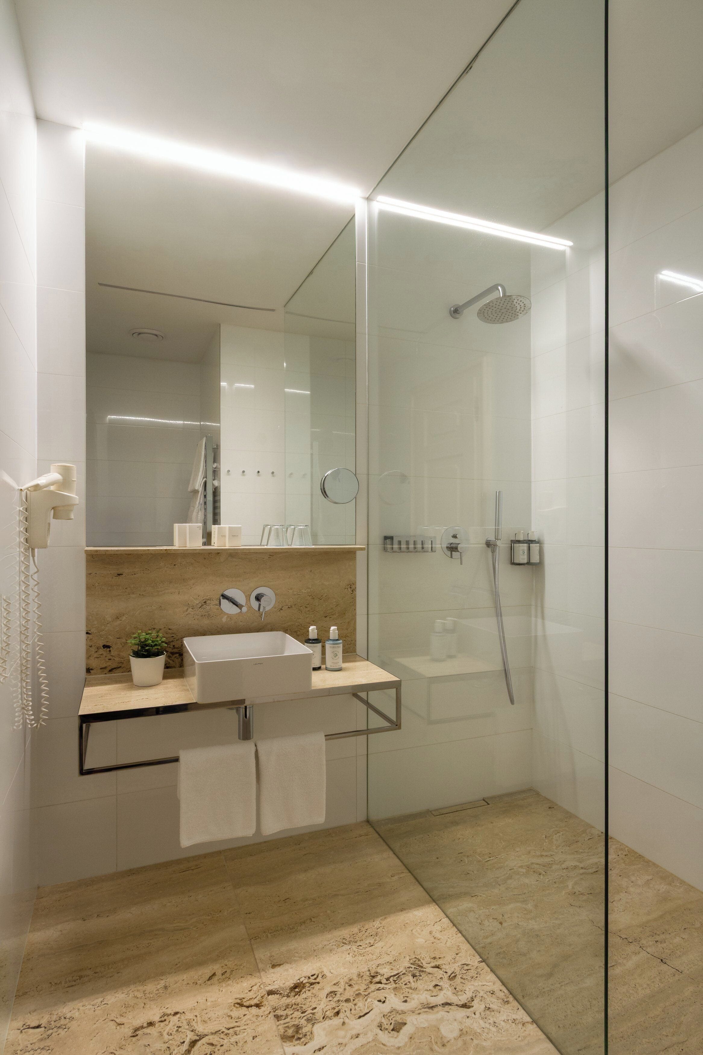 A modern bathroom with a glass-enclosed shower, a sink with a mirror, and a towel rack.