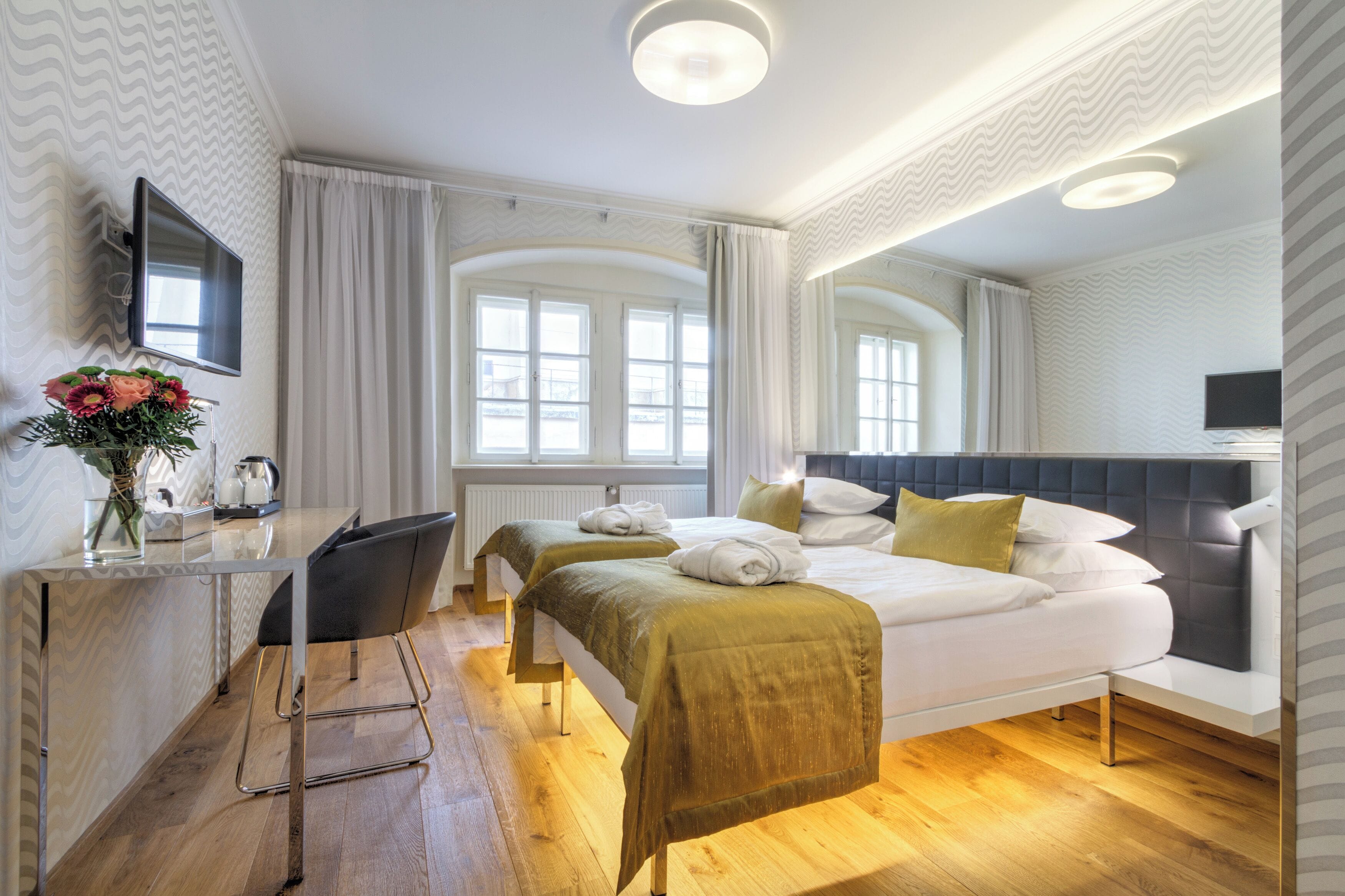 Une chambre d’hôtel comprenant un lit, des tables de chevet, un bureau, une chaise et un téléviseur.