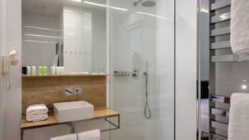 A modern bathroom with a glass-enclosed shower, a wooden vanity, and a glass-topped sink.