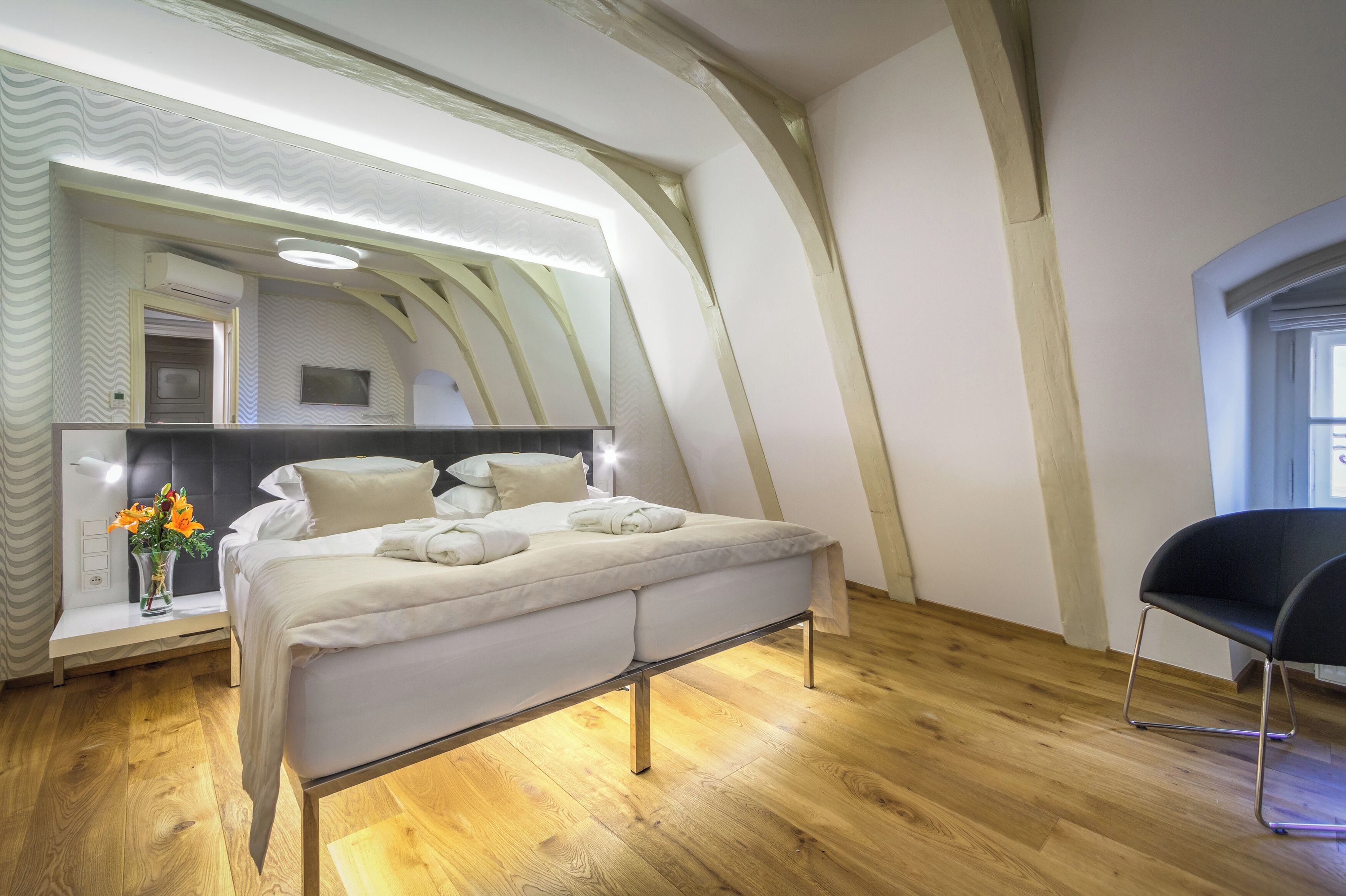 A modern bedroom with a bed, a bedside table with a vase of flowers, and a chair.