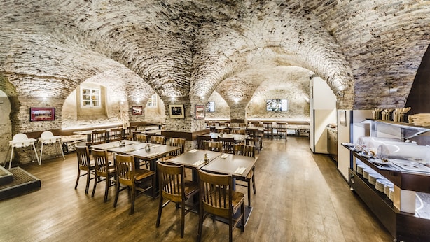 A restaurant with stone vaulted ceilings and wooden tables and chairs. - Archibald At the Charles Bridge (Prague)