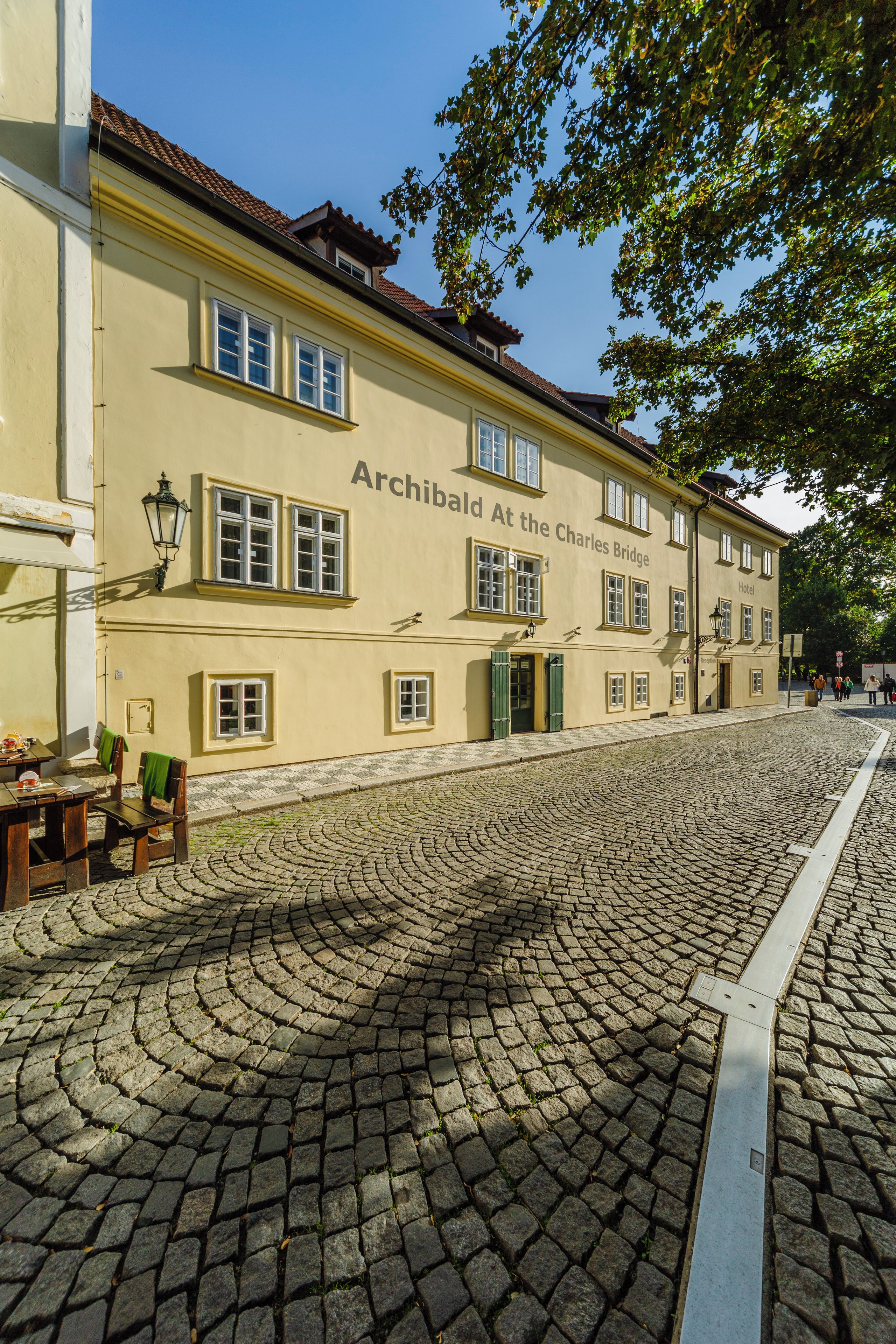 Eine Kopfsteinpflasterstraße mit einem Gebäude, auf dem 'Archibald At the Charles Bridge Hotel' steht.