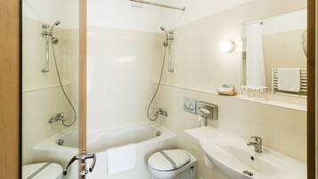 A modern bathroom with a bathtub, two toilets, a sink, and a mirror.