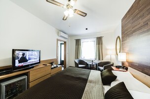 Camera d'albergo con un letto, una scrivania, una sedia, un televisore e una ventola a soffitto.