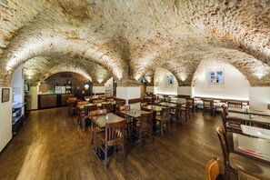 A restaurant with a rustic stone ceiling, wooden tables, and chairs. - Archibald At the Charles Bridge (Prague)