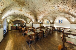 Um restaurante com teto de pedra rústica, mesas e cadeiras de madeira.