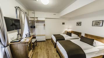 Habitación de hotel con dos camas, un escritorio con computadora, armario y televisor.