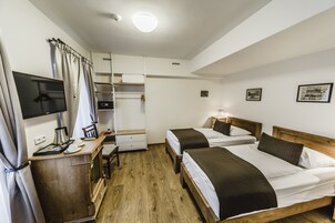 Habitación de hotel con dos camas, un escritorio con computadora, armario y televisor.