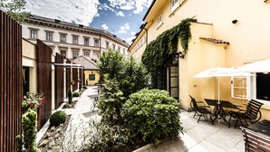 A courtyard with a patio area, outdoor seating, and a building with a yellow facade. - Archibald At the Charles Bridge (Prague)