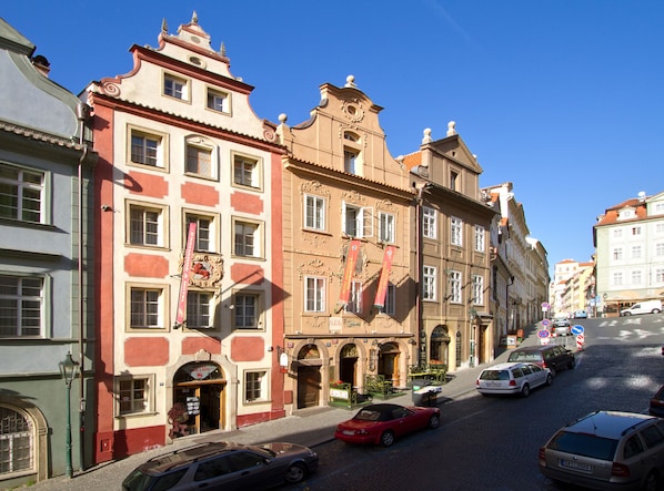 A historic building with a red and cream facade, multiple windows, and a sign for a hotel. - Red Lion (Prague)
