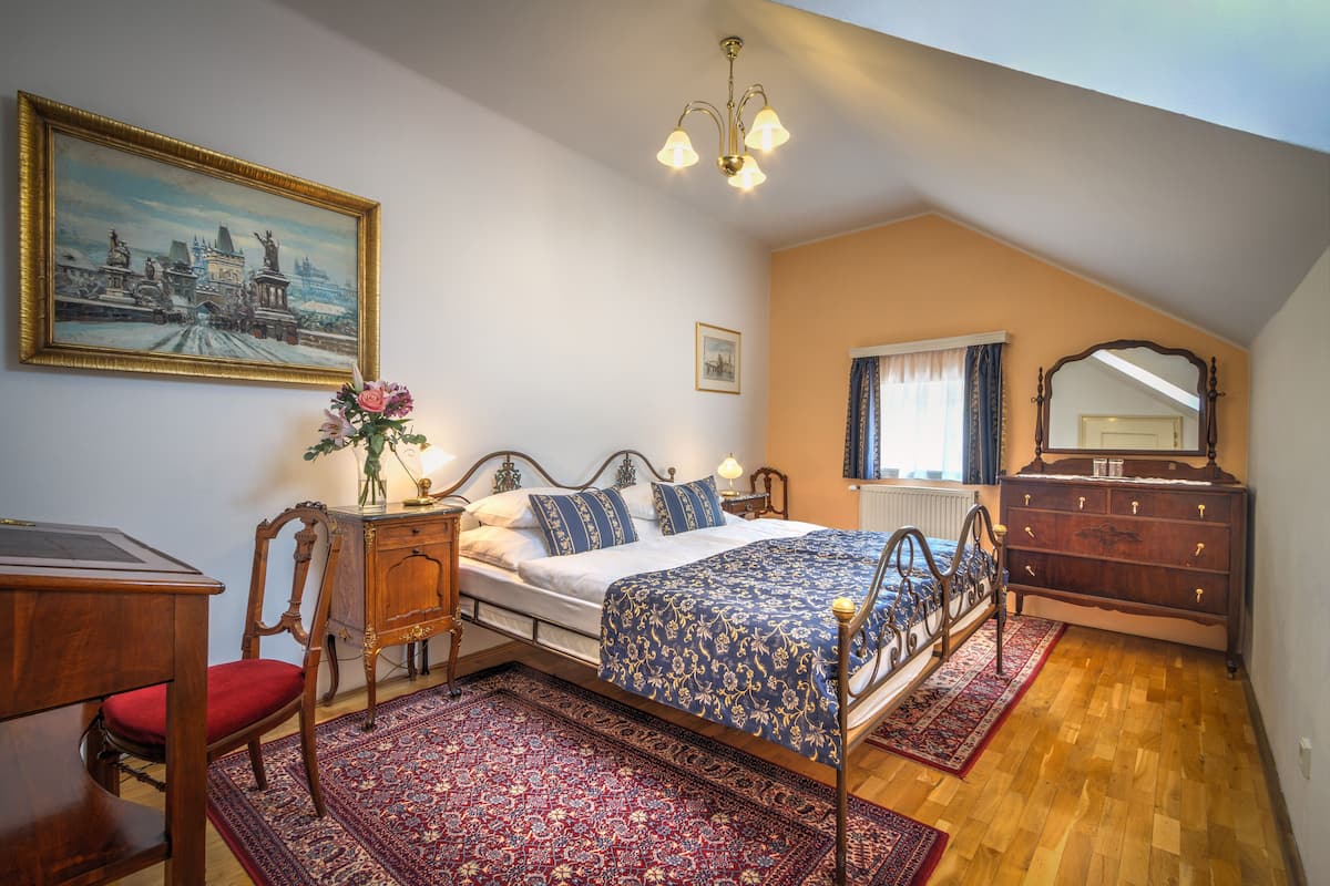 Ein Schlafzimmer mit einem Bett, einem Schminktisch, einem Stuhl, einem Schreibtisch, einem Gemälde und einer Chandelier.