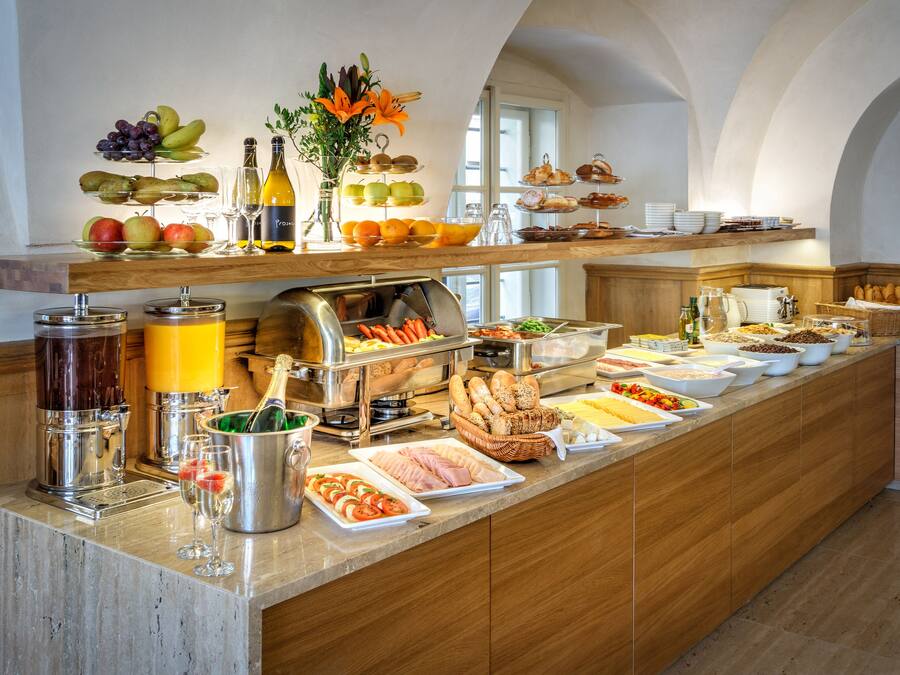 A buffet with various food items, a coffee machine, and a wine bottle.