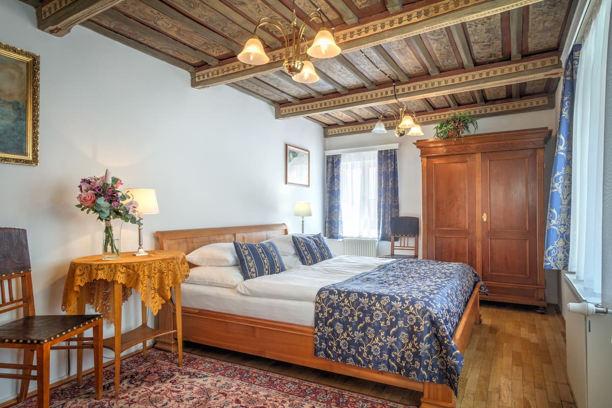Ein Schlafzimmer mit einem hölzernen Bett, einem kleinen Tisch mit Lampe, einem Sessel und einem großen Kleiderschrank.
