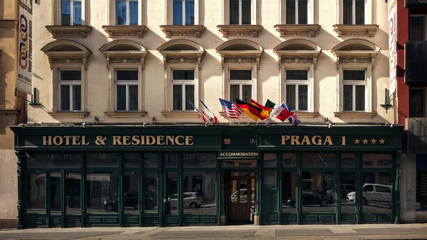 A hotel facade with multiple windows, a green entrance, and flags. - Hotel Praga 1 (Prague)