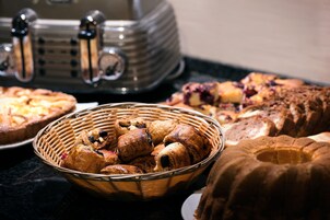 Diversos produtos de panificação em uma mesa, incluindo uma cesta de doces e um bolo bundt.
