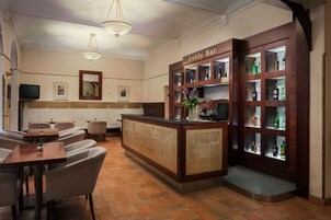 Un vestíbulo con una recepción, zona de estar y un bar con estantes llenos de botellas de licor.