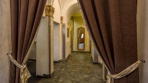 A corridor with brown curtains tied back, revealing a tiled floor and an arched ceiling. - Hotel Superior Prague (Prague)