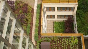 An aerial view of a rooftop garden with seating areas and a small building structure. - Hotel Superior Prague (Prague)