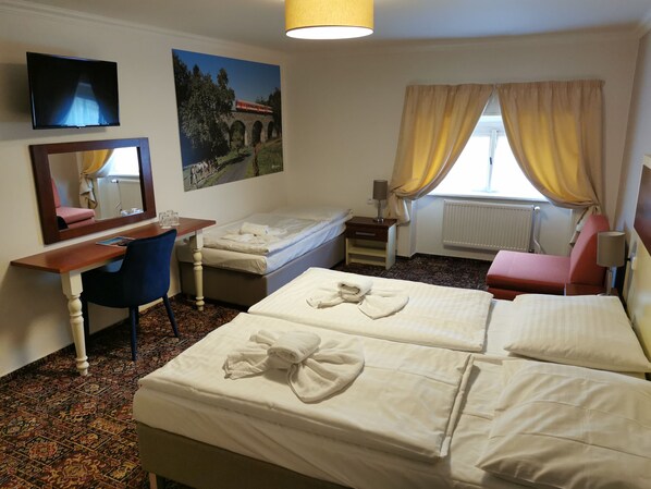 A hotel room with two beds, a desk, a chair, a TV, a window with curtains, and a painting on the wall. - City Inn (Prague)