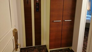 Habitación de hotel con un armario grande, una puerta con picaporte y una alfombra estampada.