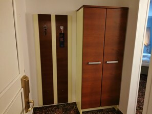 A hotel room with a large wardrobe, a door with a handle, and a patterned carpet. - City Inn (Prague)