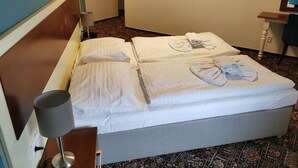 Una habitación de hotel con cama, lámpara, un cuadro de un tren en la pared y suelo alfombrado.