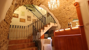 A staircase with a white chair, a wooden counter, and a chandelier. - Hotel Metamorphis (Prague)