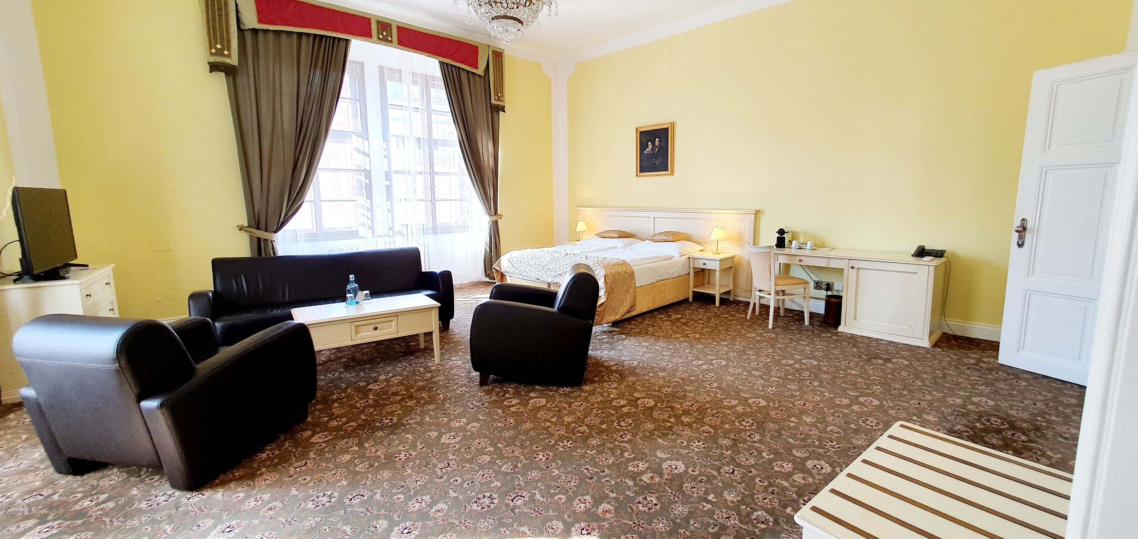 A hotel room with a bed, a desk, a sofa, and a television.