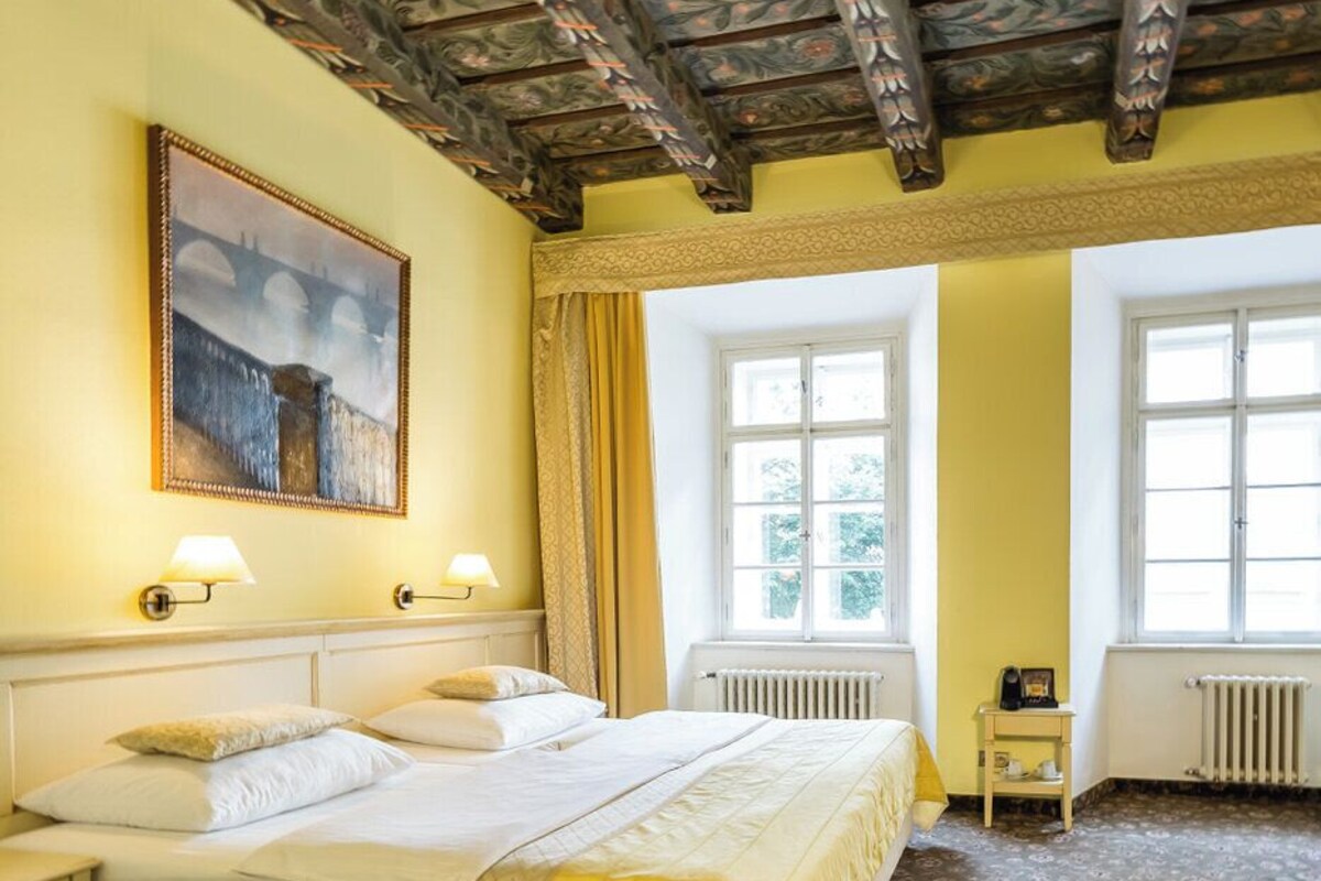 Een hotelkamer met een groot bed, twee nachtkastjes, een schilderij en een raam.